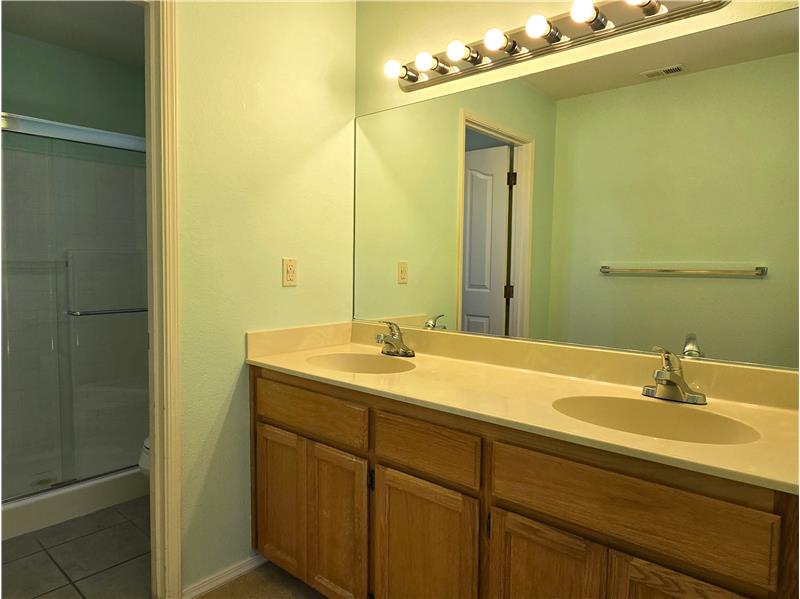 Clean and bright, the primary bath offers dual sinks, expansive mirror space, and generous lighting throughout.
