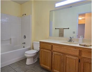 Main bath with solid-surface counter, tile flooring and tub/shower combo, ideal for family and guests.