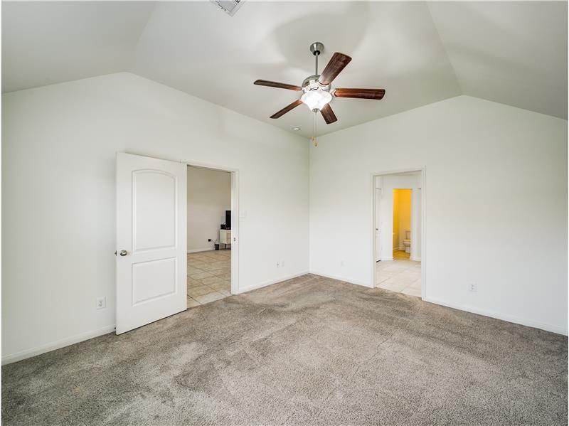 Large primary bedroom with a ceiling fan