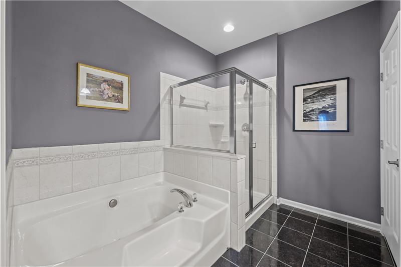 Primary bathroom features soaking tub, tile floors