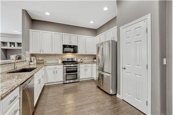 The kitchen is a chef's delight, featuring a breakfast bar, pantry, roll-out cabinetry, granite countertops, & granite sink.