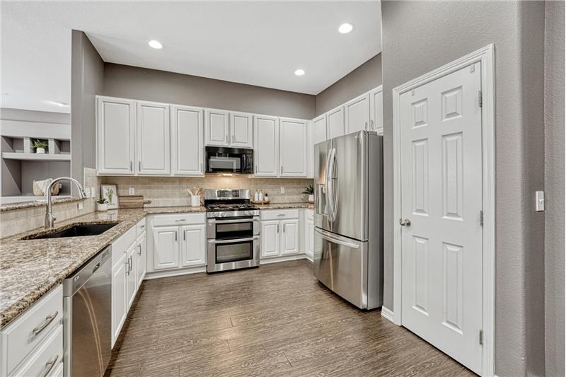 The kitchen is a chef's delight, featuring a breakfast bar, pantry, roll-out cabinetry, granite countertops, & granite sink.