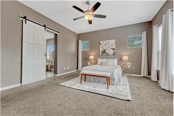 The private Primary Suite offers neutral carpet, a walk-in closet, ceiling fan, and a luxurious 5-piece bath.