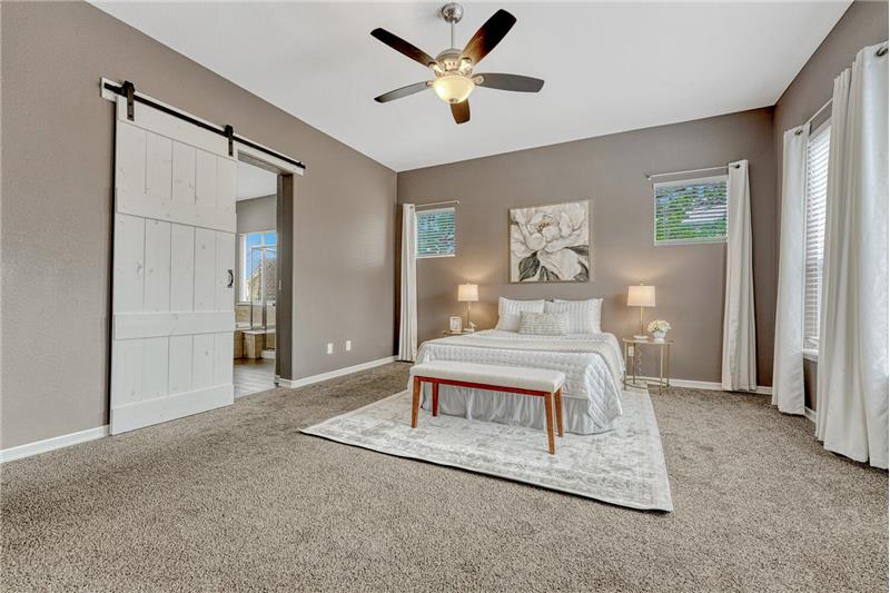 The private Primary Suite offers neutral carpet, a walk-in closet, ceiling fan, and a luxurious 5-piece bath.