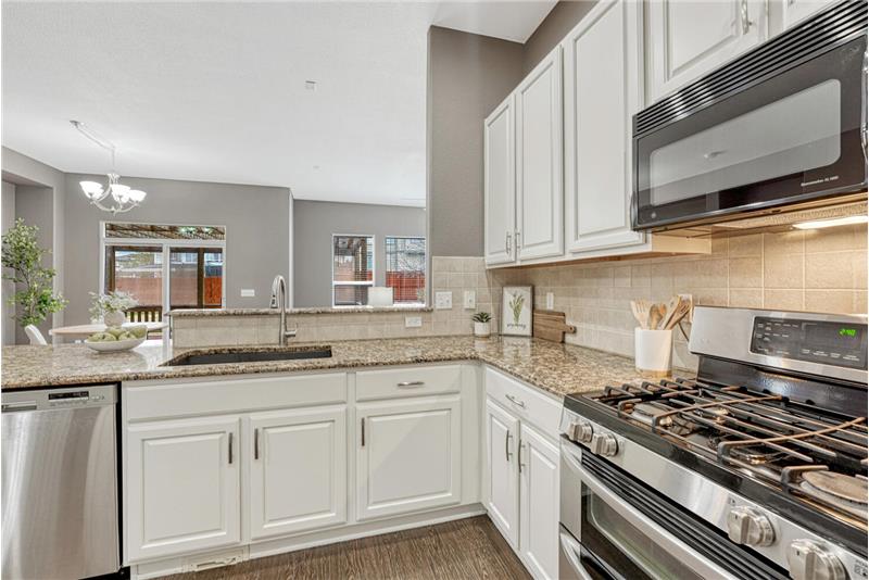 White cabinetry with roll-out shelving and beautiful granite countertops and composite granite sink.