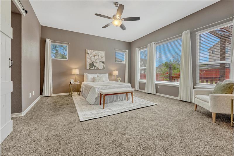 The Primary Bedroom provides a private retreat with neutral carpet, a lighted ceiling fan, wall of windows, & adjoining 5pc Bath