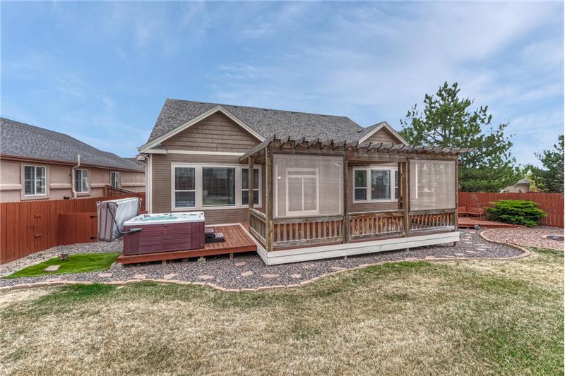 Fenced backyard with deck, pergola, and hot tub.