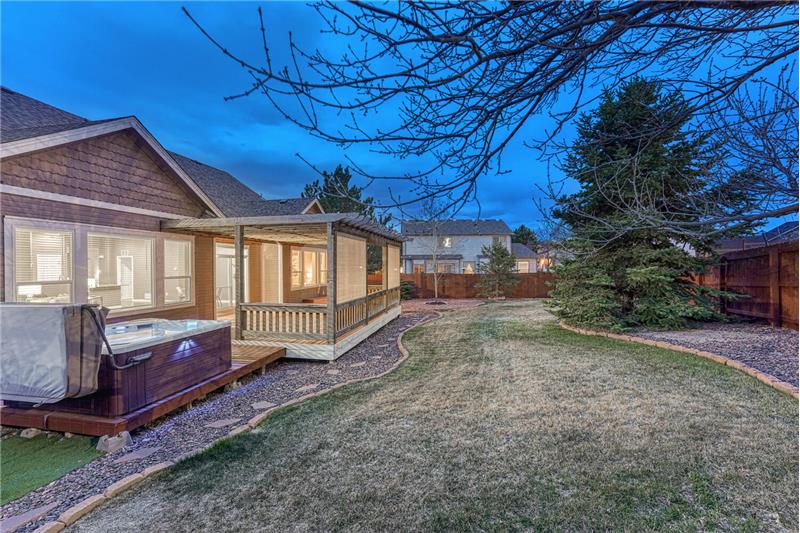 Sunset views of the Backyard with auto sprinklers, mature trees, built-in fire pit, deck, pergola, and hot tub..