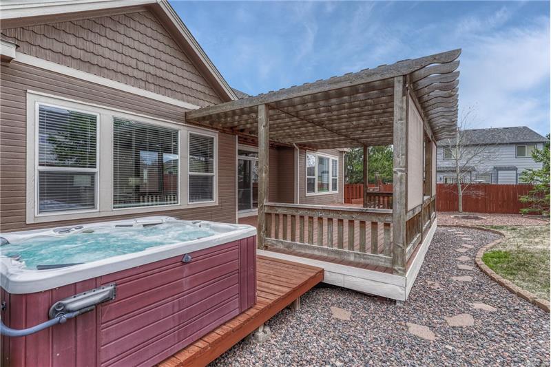 Backyard hot tub and deck with pergola.