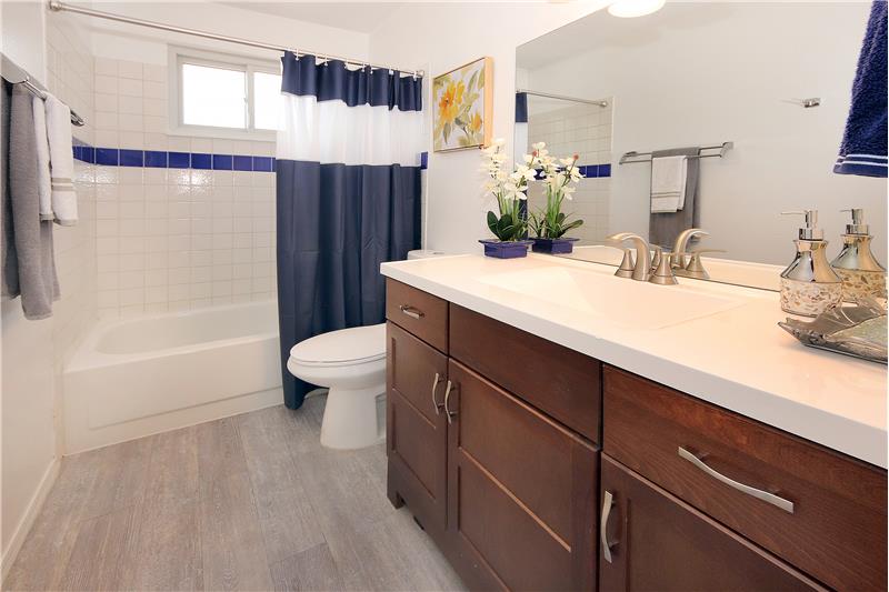Main level full bath with wood laminate flooring, large linen closet, and large vanity!