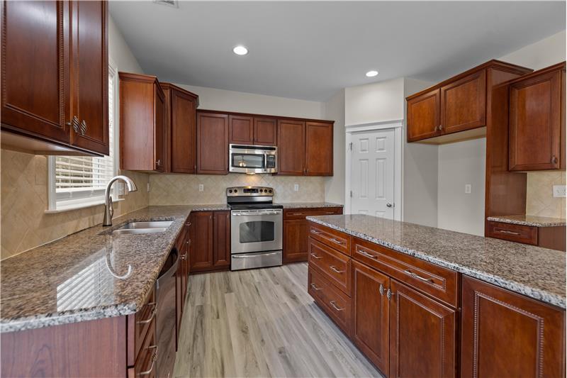 42 inch cherry cabinets with crowns, granite counters, tile backsplash, stainless steel appliances.