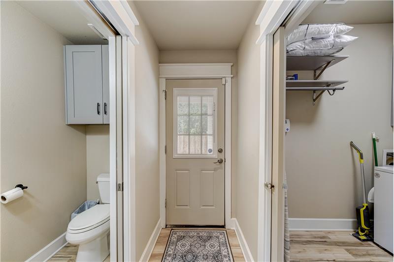 Hallway with half bath and laundry with exit to carport.