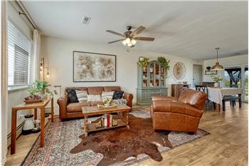 Living Room with beautiful LVP flooring, lighted ceiling fan, and large window for natural light.
