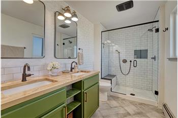 Primary Bathroom with tile floor, dual sink vanity, framed mirror, and tiled walk-in shower.