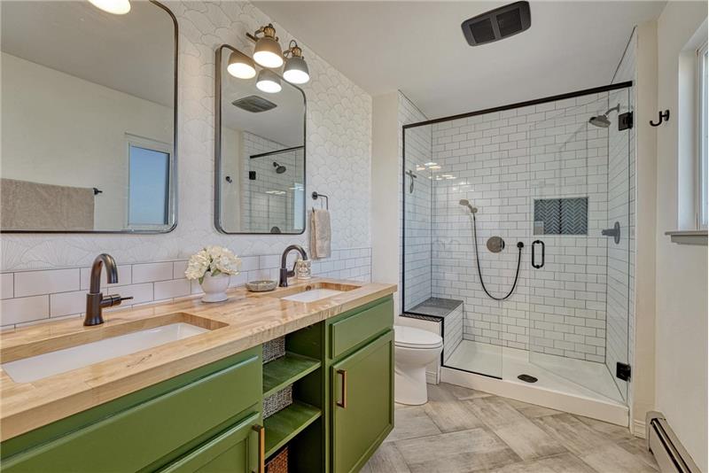 Primary Bathroom with tile floor, dual sink vanity, framed mirror, and tiled walk-in shower.
