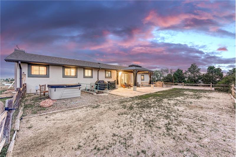 Sunset rear view of home, backyard, and patio with pergola.