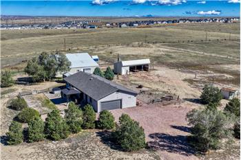 Aerial view of home, lot, and out buiidngs with mountain views.