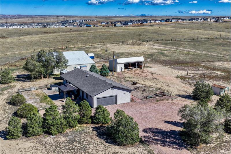 Aerial view of home, lot, and out buiidngs with mountain views.