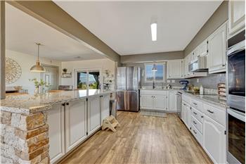 The Kitchen boasts white cabinets, granite countertops, induction cooktop, double ovens, dishwasher, microwave, & refrigerator.