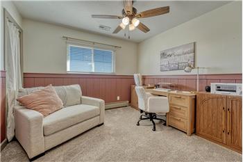 Bedroom #1 (currently an office) with carpet and lighted ceiling fan.