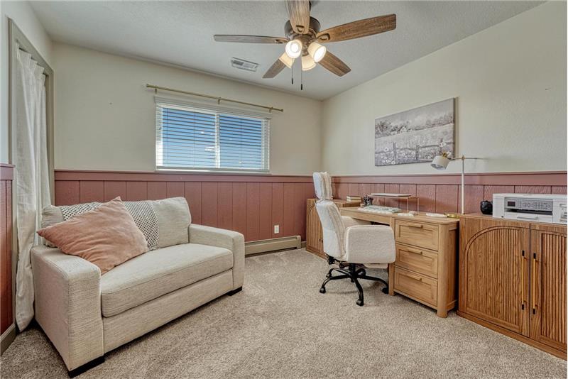 Bedroom #1 (currently an office) with carpet and lighted ceiling fan.