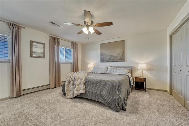 Primary Bedroom with neutral carpet, lighted ceiling fan, spacious closet, and adjoining Bathroom.