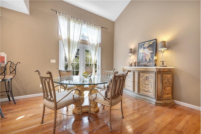 Dining room has wood floor, patio door, transom window, vaulted ceiling.