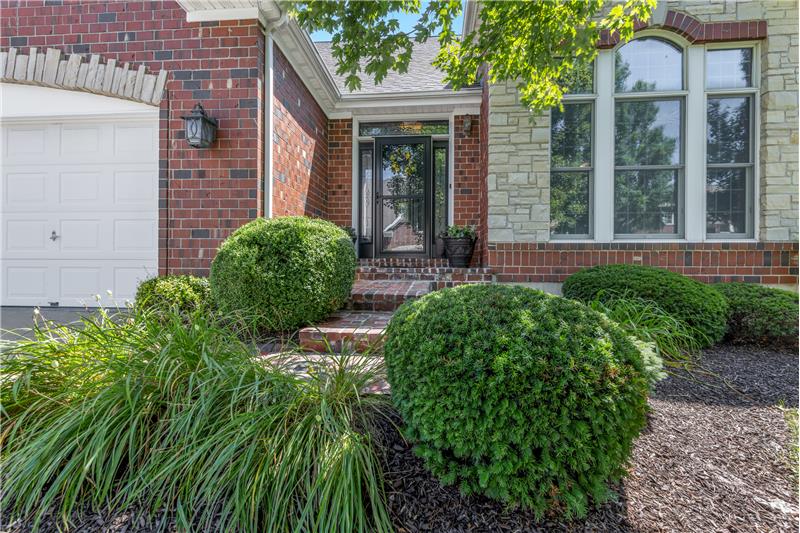Front door  with lush landscaping maintained by the association.