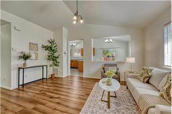 Spacious vaulted living room, featuring durable LVP floors, an attractive light fixture, & convenient coat closet.