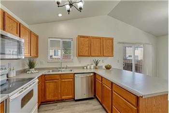 Well-designed kitchen offers wood laminate flooring, wood cabinetry, a pantry, & abundant counter space.