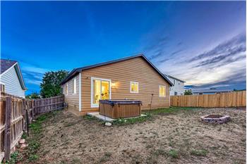 Large fenced backyard with sprinkler system, patio, raised flower bed, and hot tub.