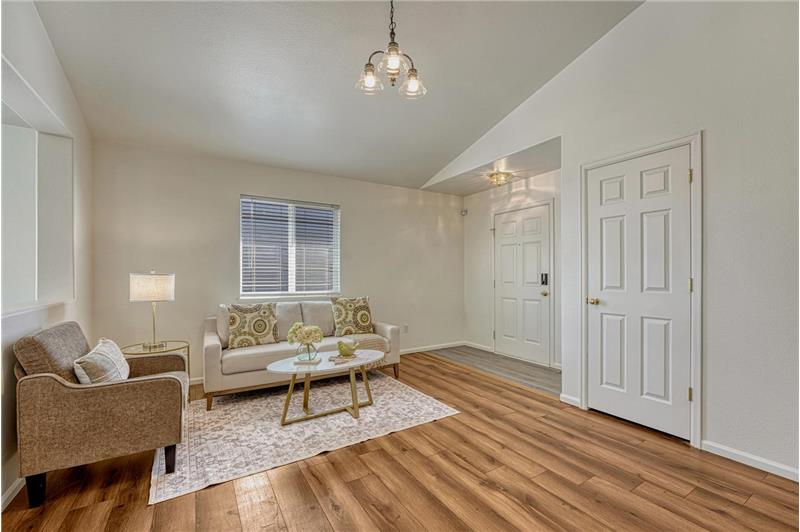 Spacious vaulted Living Room with LVP flooring, an attractive light fixture, and convenient coat closet.