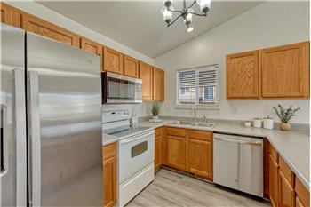 Kitchen appliances include a stainless steel side by side refrigerator, smooth top range/oven, microwave, and dishwasher.