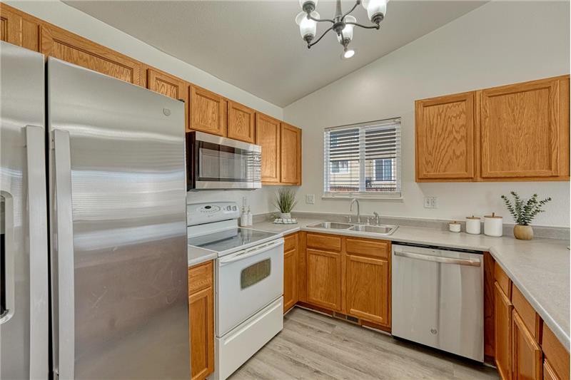 Kitchen appliances include a stainless steel side by side refrigerator, smooth top range/oven, microwave, and dishwasher.