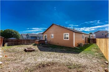 Rear view of home and fenced backyard.