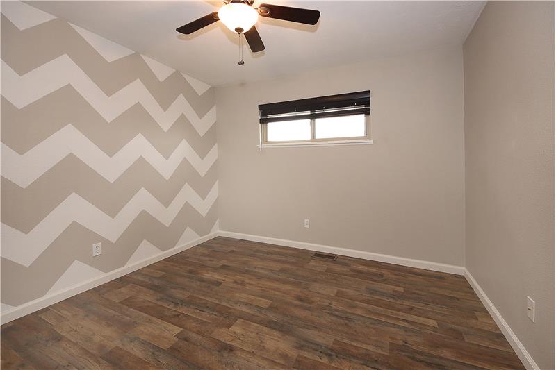 Main level bedroom with ceiling fan and new flooring