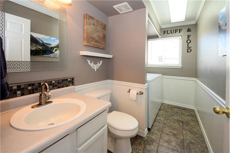Updated half bath on main level with laundry room (washer/dryer included), tile flooring, and wainscoting.