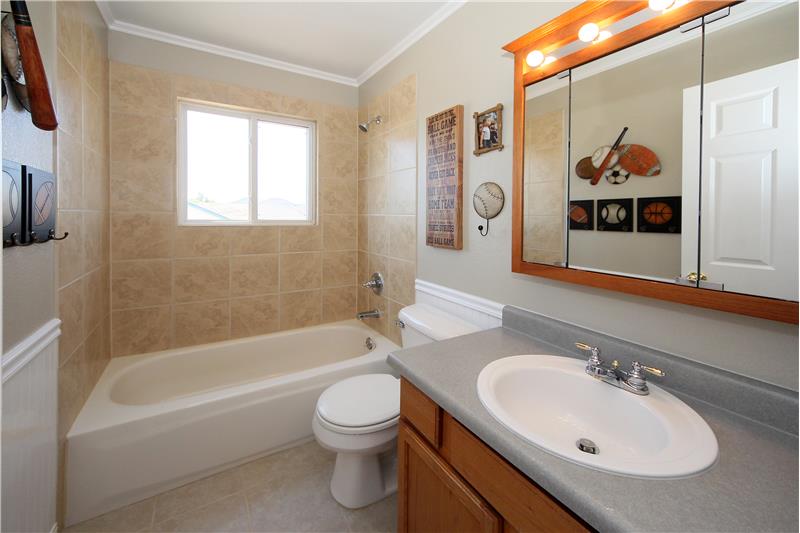 Full bath on upper level with tile floors, tile bath surround, and wainscoting