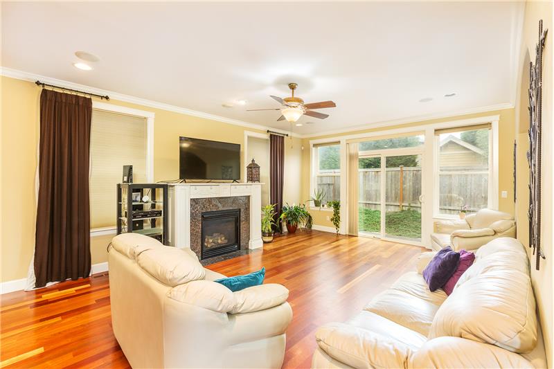 Large, Cozy Living Room with Gleaming Brazilian Cherry Hardwood Floors and Elegant Gas, Granite Slab Surround Fireplace. Slider