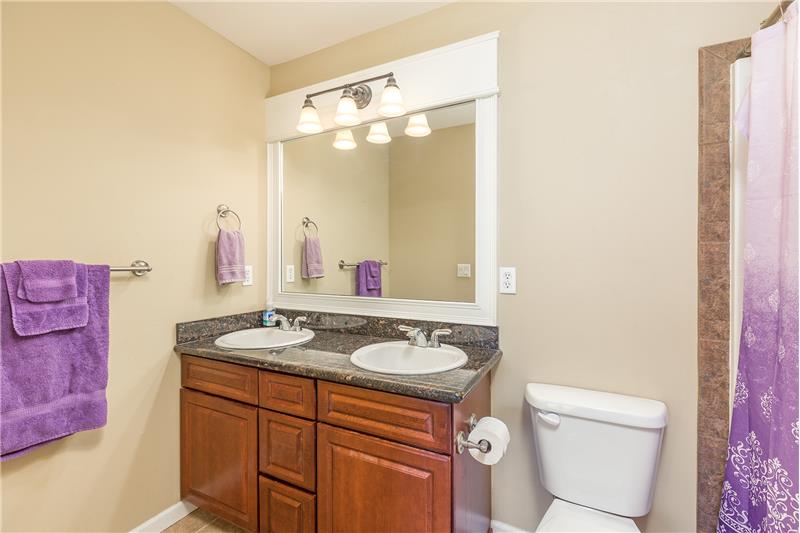 Upstairs Full Sized Bathroom with Dual Sinks and Tile Surround Shower and Granite Counter Tops.
