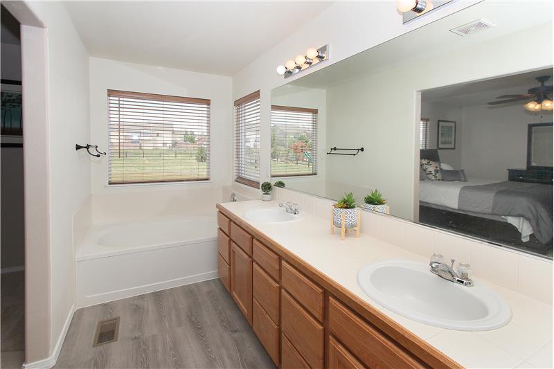 Master bathroom with new flooring, double sink vanity, soaking tub, and separate shower