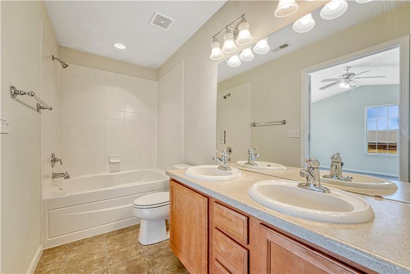 Adjoining bath to Primary Bedroom #2 with tub/shower combo, double sinks, and medicine cabinet