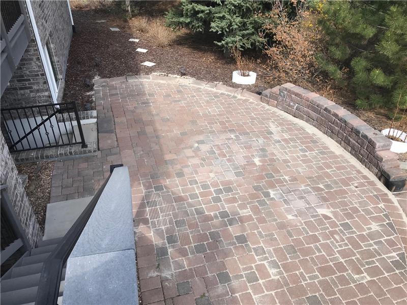 View of patio from main-floor deck. Notice the short stairway to basement at left.