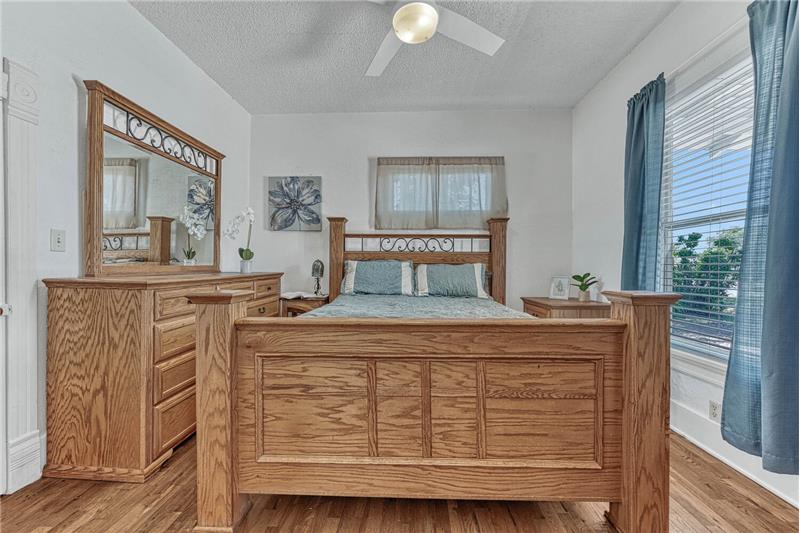 Primary bedroom on the main floor with ceiling fan and hardwood flooring