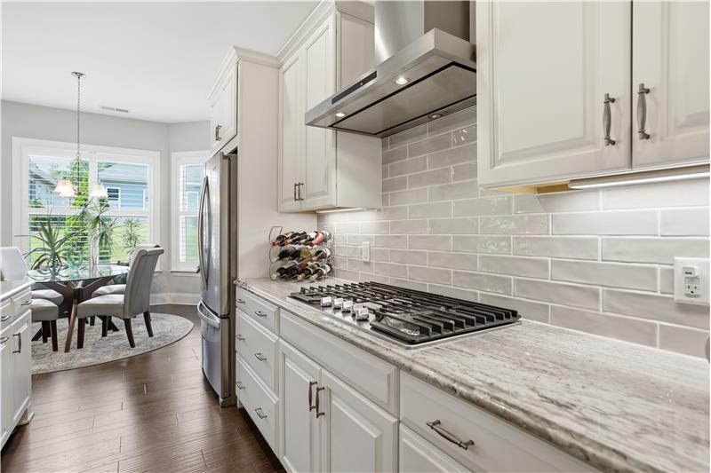 Crisp, white cabinetry plus gas cooktop, integrated wall oven/microwave and full-height tile backsplash add a polished finish.