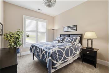 One of two secondary bedrooms in this split bedroom plan, featuring plantation shutters, designer fan, neutral decor.