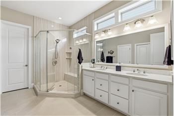 Primary bathroom has double sink vanity; oversized, glass shower with bench & tile surround; tile floors; walk-in closet.