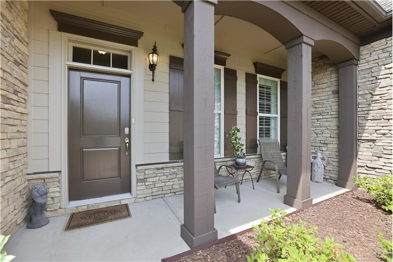 Front porch creates an inviting first impression. Stacked stone accents, rich wood-toned columns, arched beams add character.