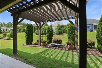 Covered patio extends to a pergola with landscaped surroundings.