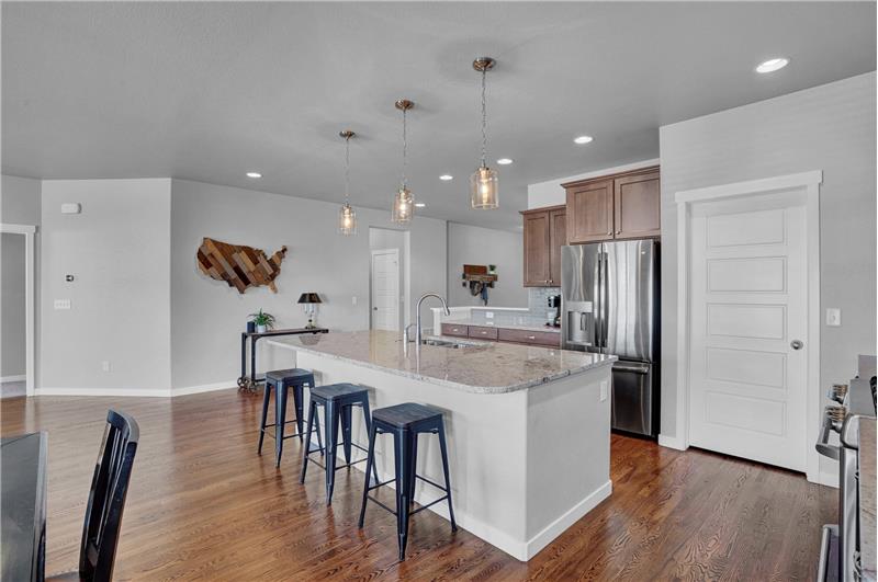 Gourmet Island Kitchen with counter bar, pendant lights, walk in pantry, and stacked cabinets with granite countertops